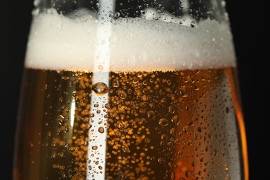 Photo of Glass of beer with condensation drops on black background, macro view