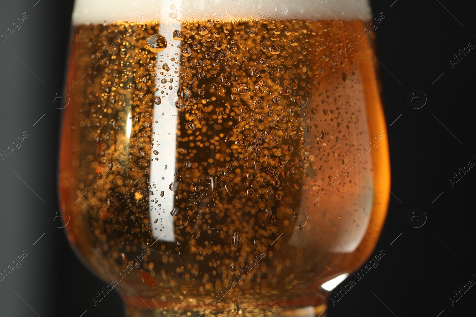 Photo of Glass of beer with condensation drops on black background, macro view