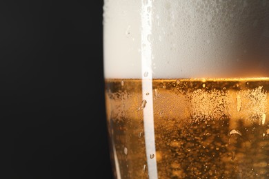 Photo of Glass of beer with condensation drops on black background, macro view. Space for text