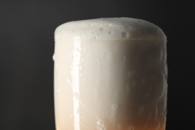 Photo of Glass of beer with foam on black background, closeup