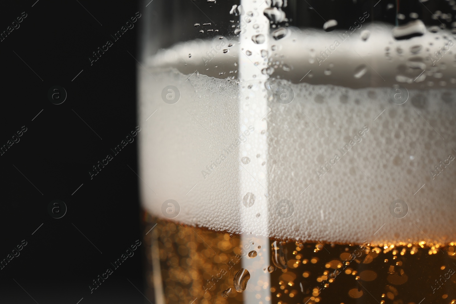 Photo of Glass of beer with condensation drops on black background, macro view. Space for text