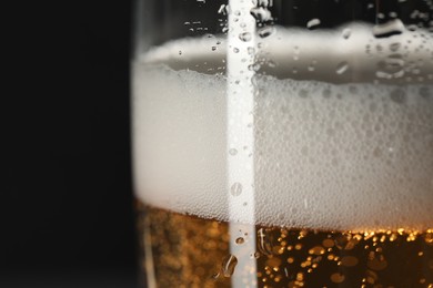 Photo of Glass of beer with condensation drops on black background, macro view. Space for text