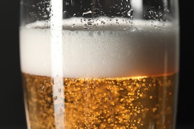 Photo of Glass of beer with condensation drops on black background, macro view