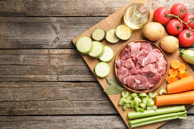 Photo of Cooking stew. Uncooked meat and vegetables on wooden table, top view. Space for text