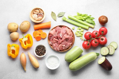 Cooking stew. Uncooked meat and vegetables on light grey table, flat lay