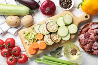 Photo of Cooking stew. Uncooked meat and vegetables on white wooden table, flat lay