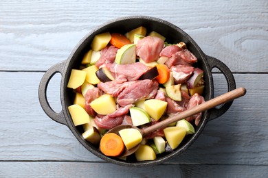 Photo of Cooking stew. Uncooked meat and vegetables in pot on light grey table, top view