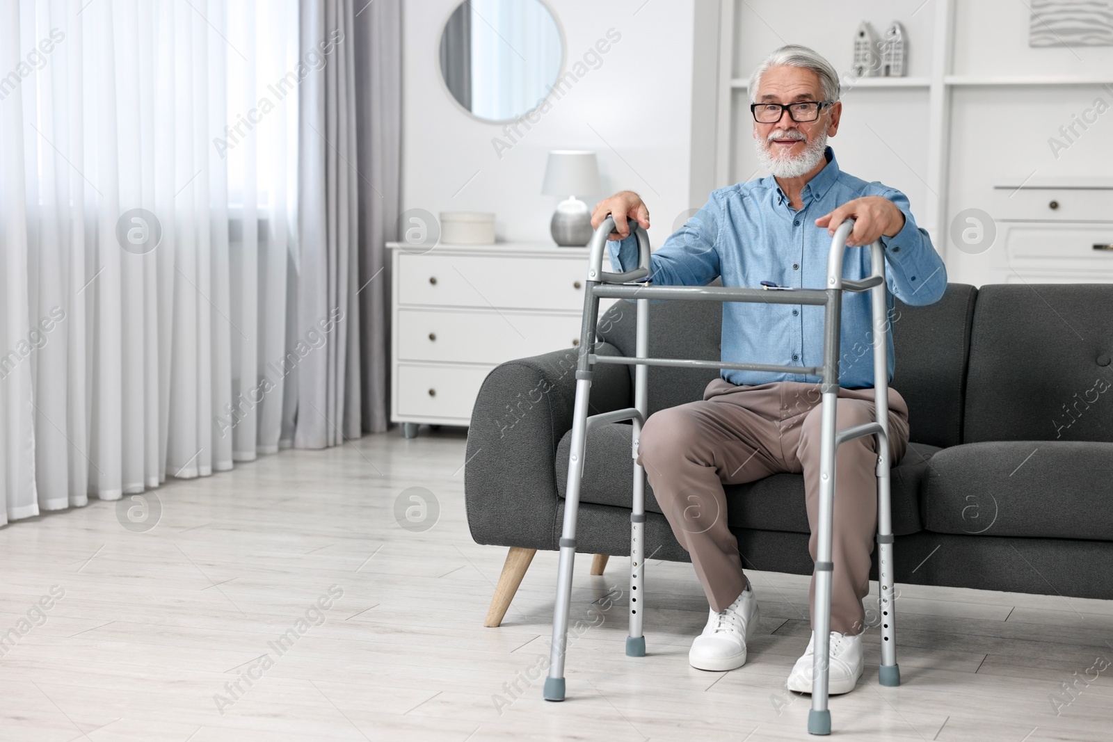 Photo of Senior man with walking frame on sofa at home