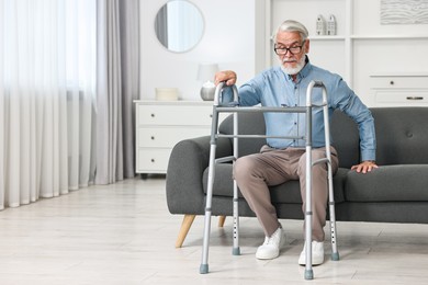 Photo of Senior man with walking frame on sofa at home