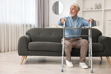 Photo of Senior man with walking frame on sofa at home