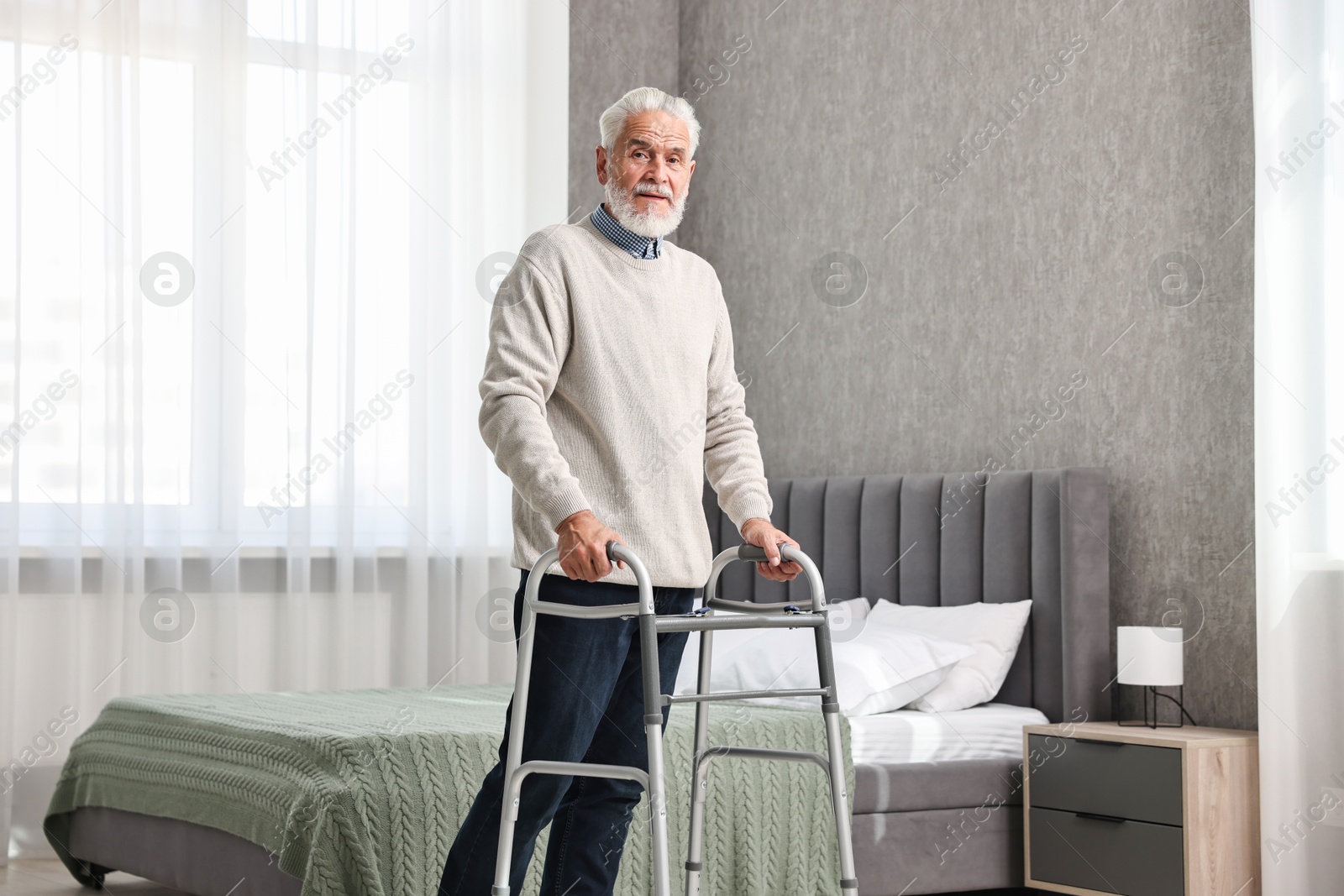 Photo of Senior man using walking frame at home