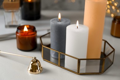 Photo of Beautiful burning candles on light table against blurred lights, closeup