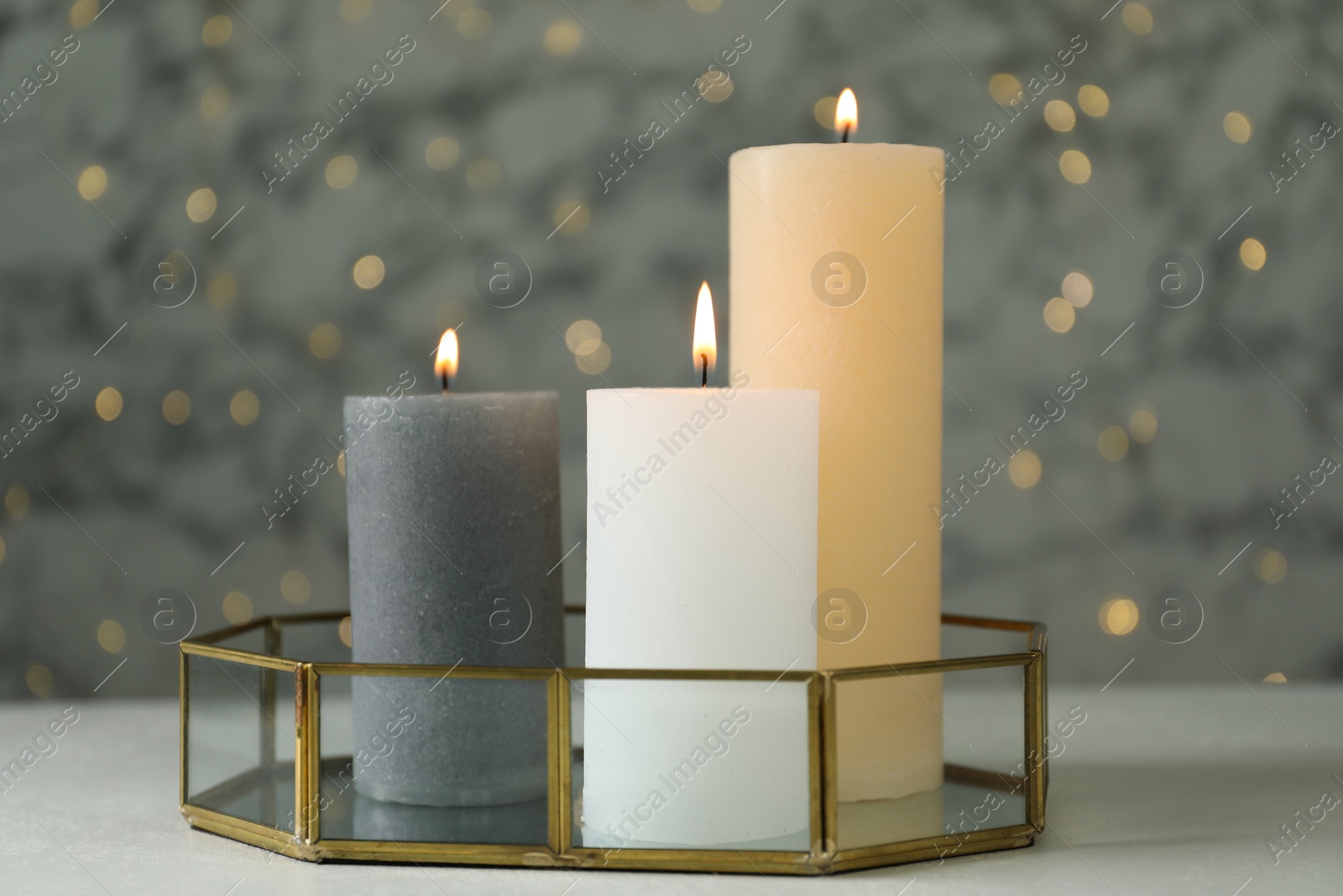 Photo of Beautiful burning candles on light table against blurred lights