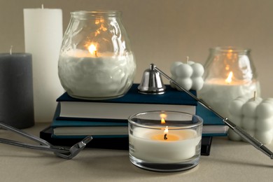 Photo of Beautiful burning candles, books, candle snuffer and wick trimmer on gray table, closeup