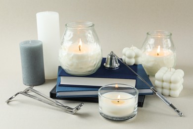 Beautiful burning candles, books, candle snuffer and wick trimmer on light background