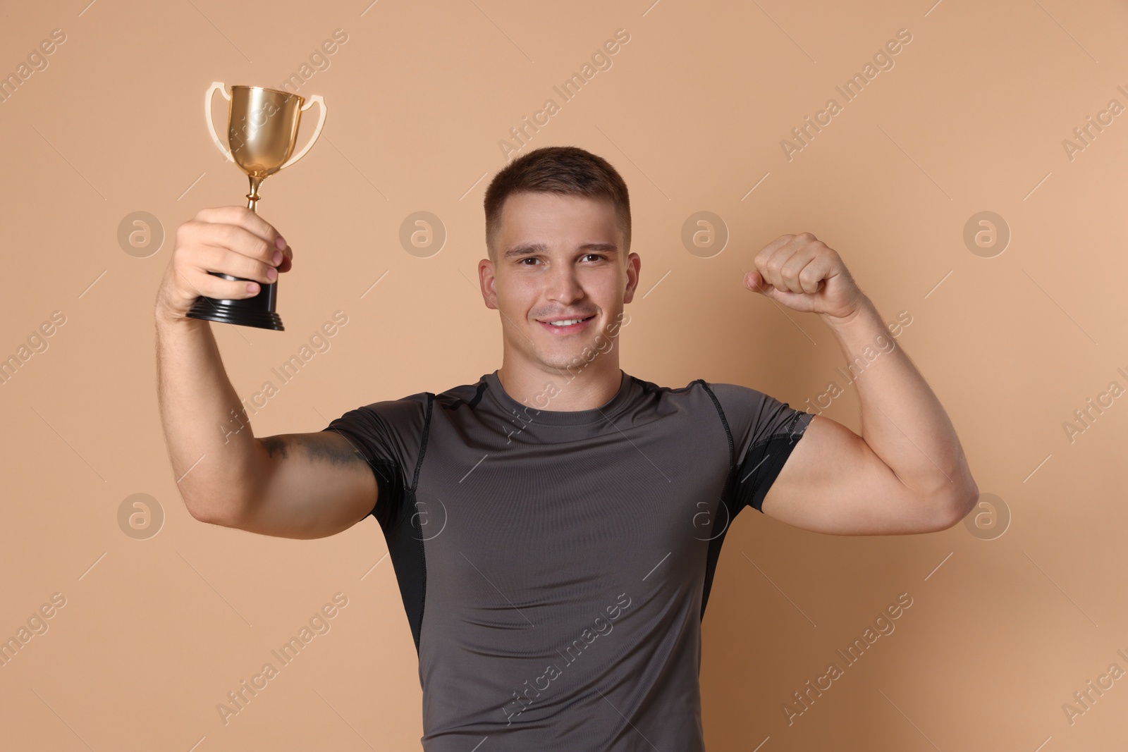 Photo of Happy winner with golden trophy cup on beige background