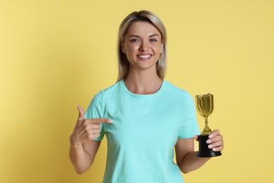 Happy winner with golden trophy cup on yellow background