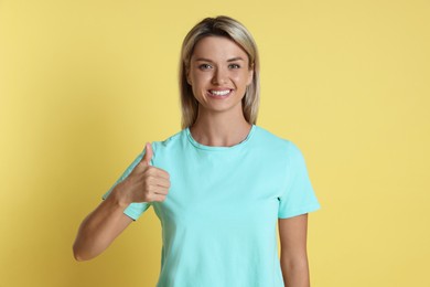 Photo of Happy winner showing thumbs up on yellow background