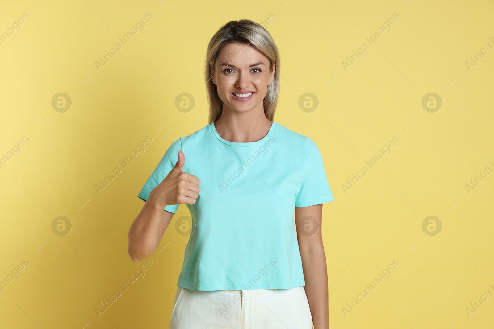 Photo of Happy winner showing thumbs up on yellow background