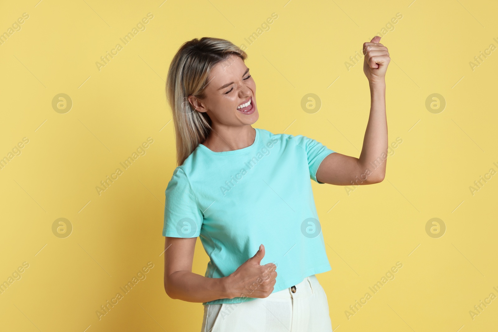 Photo of Portrait of happy winner on yellow background