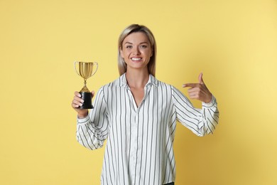 Photo of Happy winner with golden trophy cup on yellow background