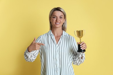 Happy winner with golden trophy cup on yellow background