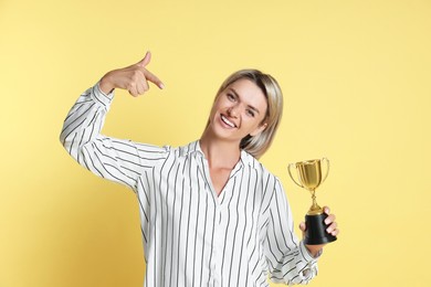 Happy winner with golden trophy cup on yellow background