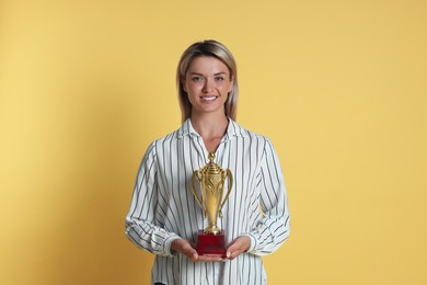 Happy winner with golden trophy cup on yellow background