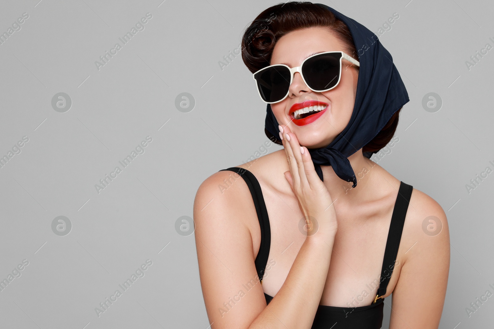 Photo of Pin-up woman in sunglasses on grey background, space for text