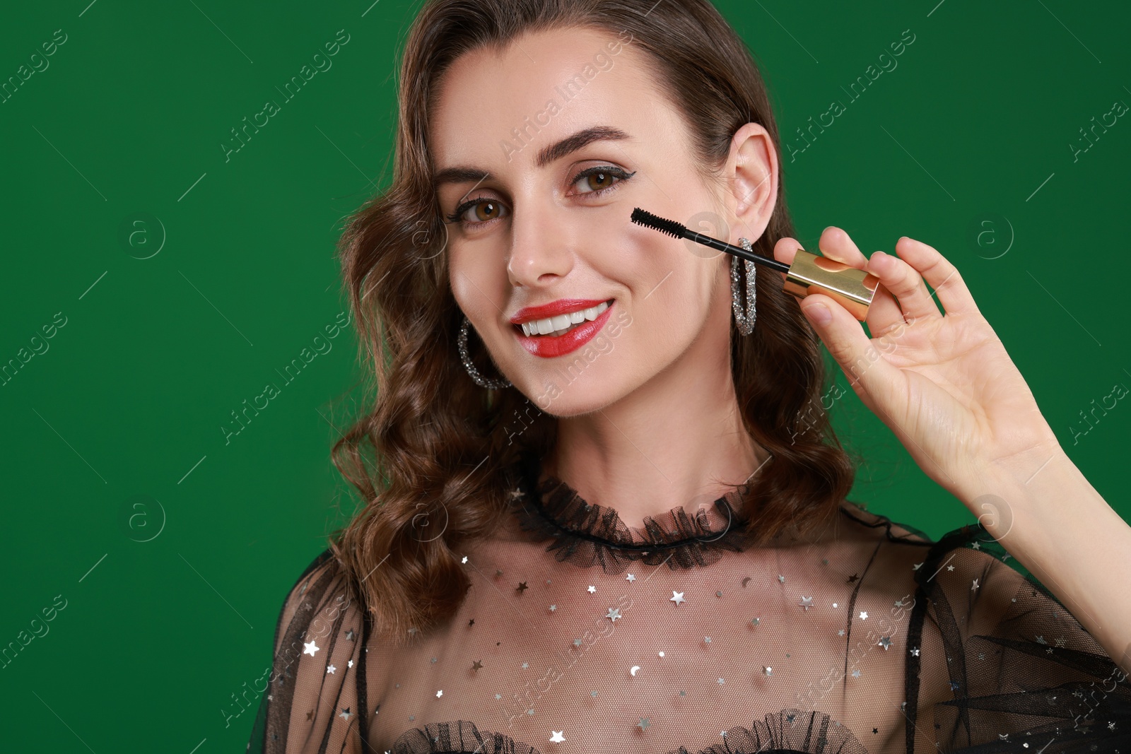 Photo of Smiling woman with makeup brush on green background