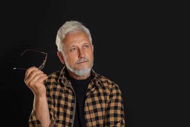 Portrait of senior man on black background, space for text