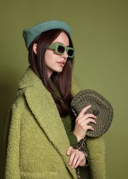 Photo of Young woman with stylish accessories on olive background