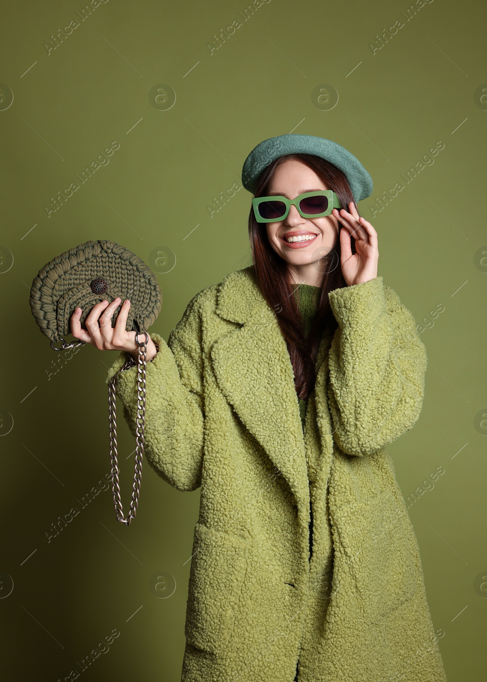 Photo of Young woman with stylish accessories on olive background