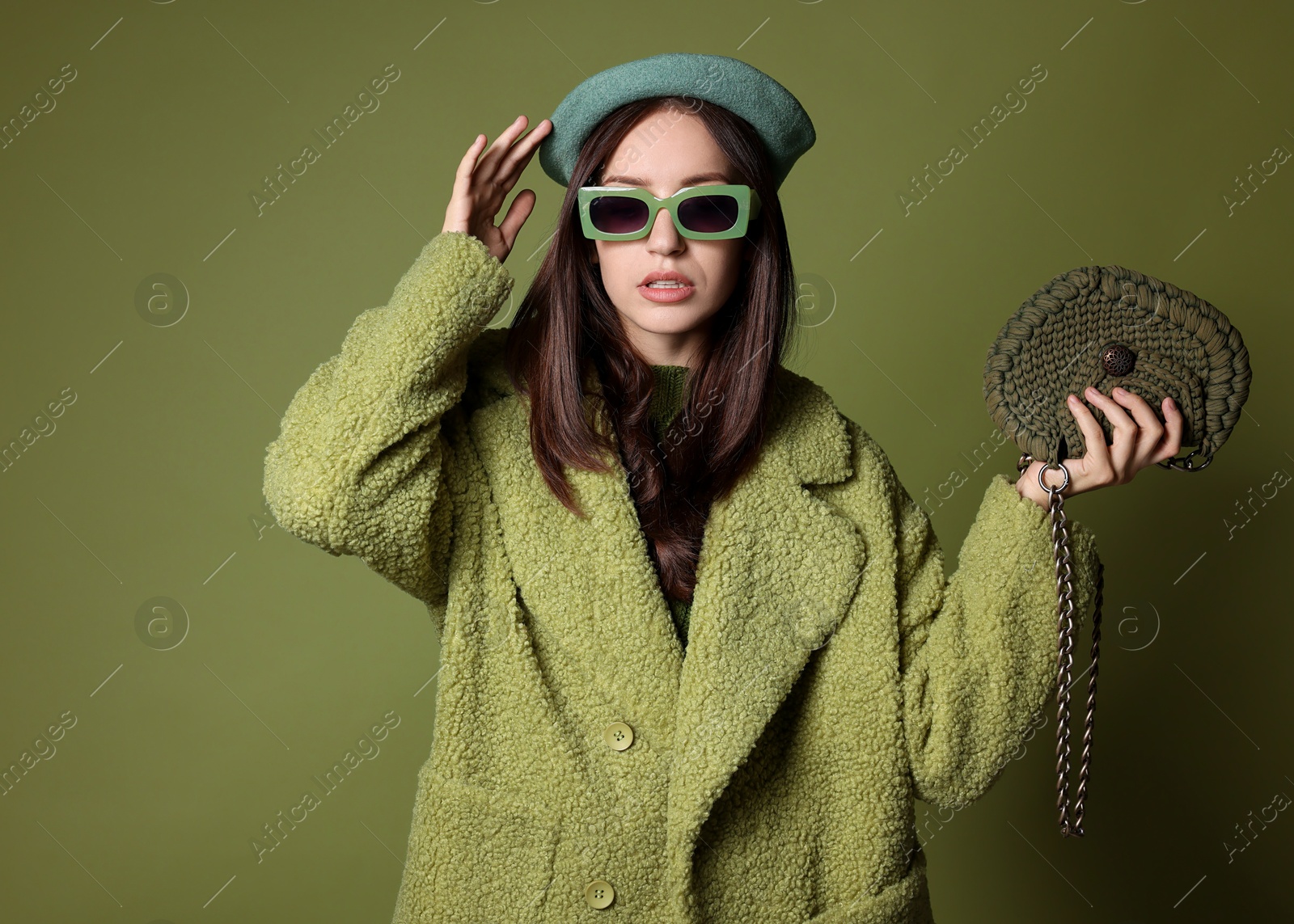 Photo of Young woman with stylish accessories on olive background