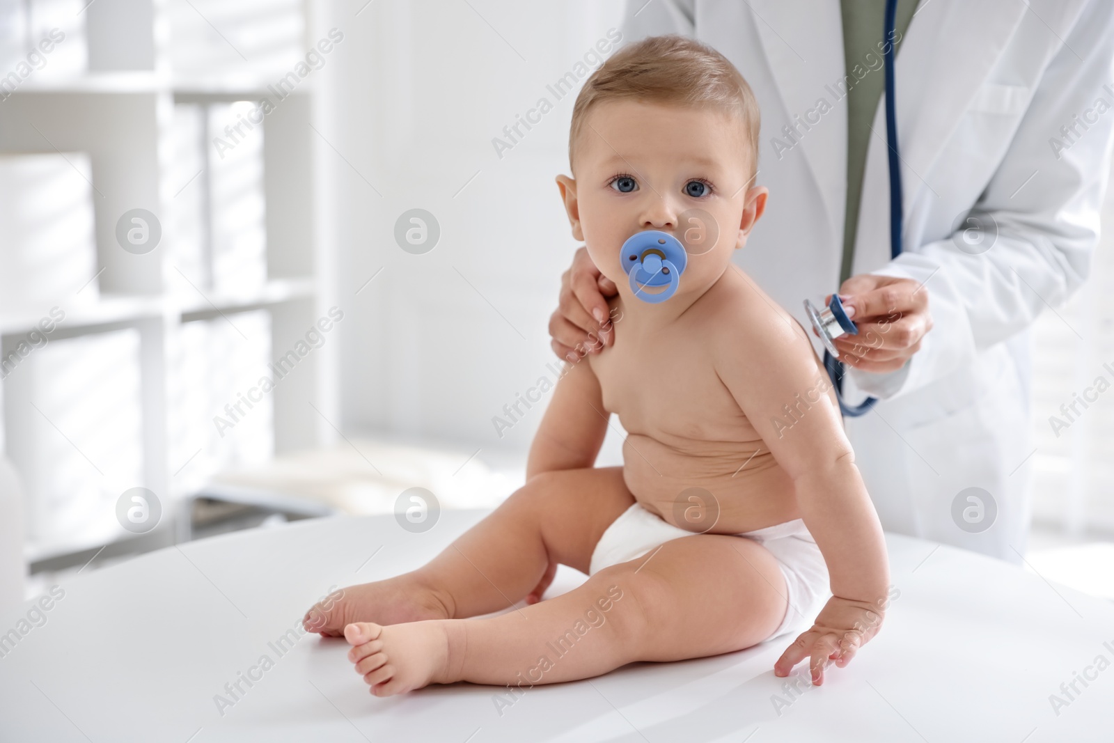 Photo of Pediatrician examining little child with stethoscope in clinic, closeup. Checking baby's health