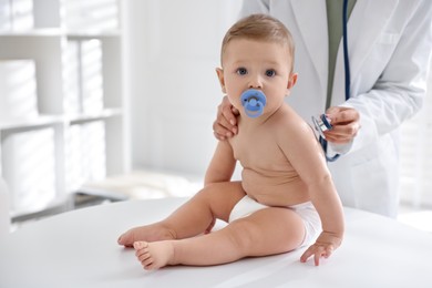 Photo of Pediatrician examining little child with stethoscope in clinic, closeup. Checking baby's health