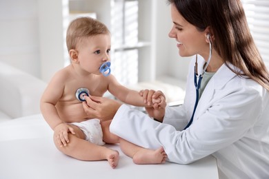 Photo of Pediatrician examining little child with stethoscope in clinic. Checking baby's health