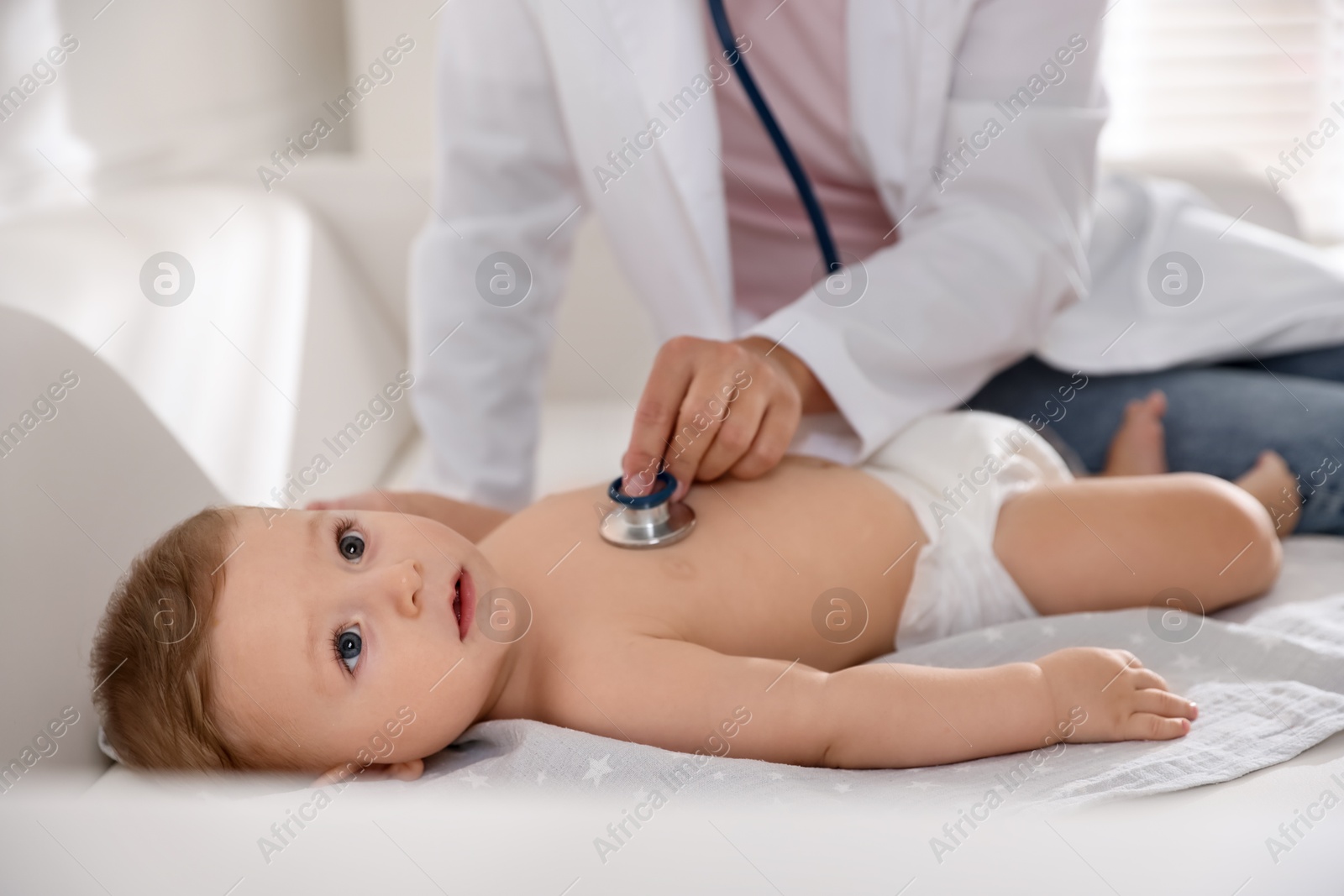 Photo of Pediatrician examining little child with stethoscope in clinic, closeup. Checking baby's health