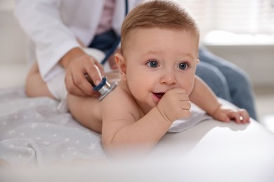 Photo of Pediatrician examining little child with stethoscope in clinic, closeup. Checking baby's health