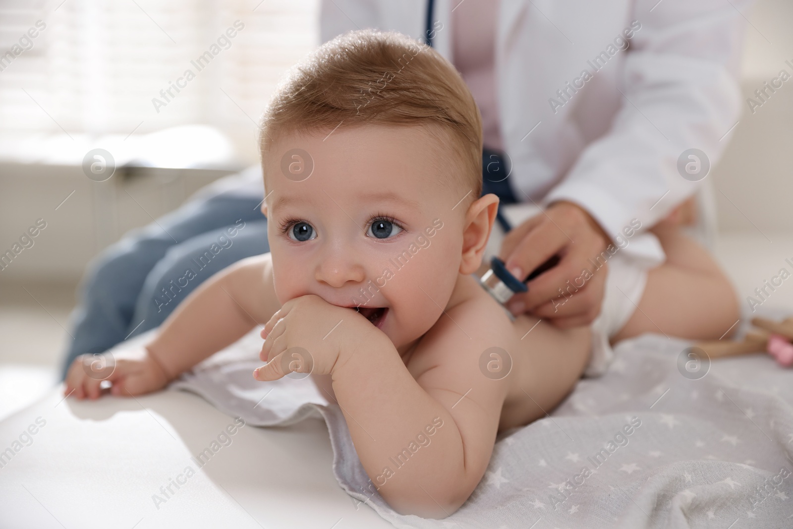 Photo of Pediatrician examining little child with stethoscope in clinic, closeup. Checking baby's health