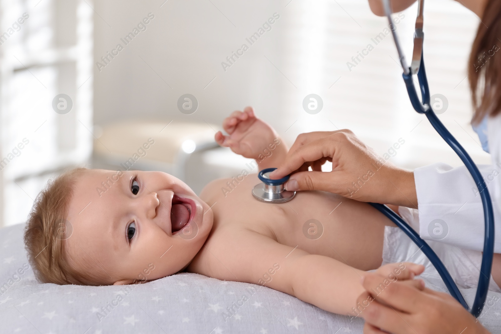 Photo of Pediatrician examining little child with stethoscope in clinic, closeup. Checking baby's health