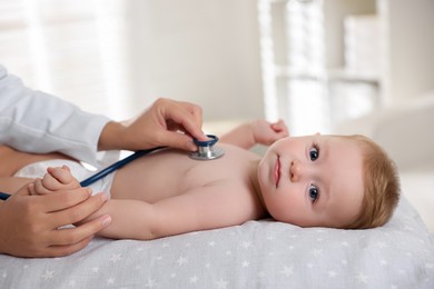 Photo of Pediatrician examining little child with stethoscope in clinic, closeup. Checking baby's health