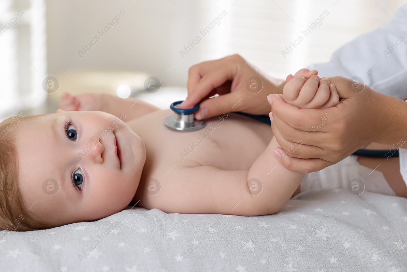 Photo of Pediatrician examining little child with stethoscope in clinic, closeup. Checking baby's health