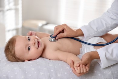 Photo of Pediatrician examining little child with stethoscope in clinic, closeup. Checking baby's health