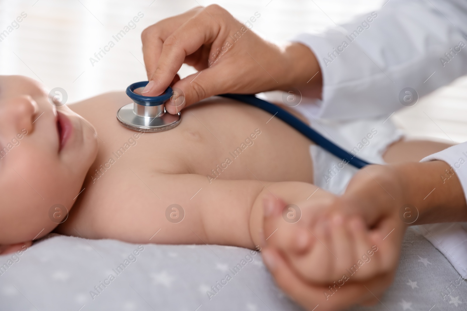 Photo of Pediatrician examining little child with stethoscope in clinic, closeup. Checking baby's health