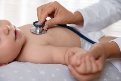 Photo of Pediatrician examining little child with stethoscope in clinic, closeup. Checking baby's health