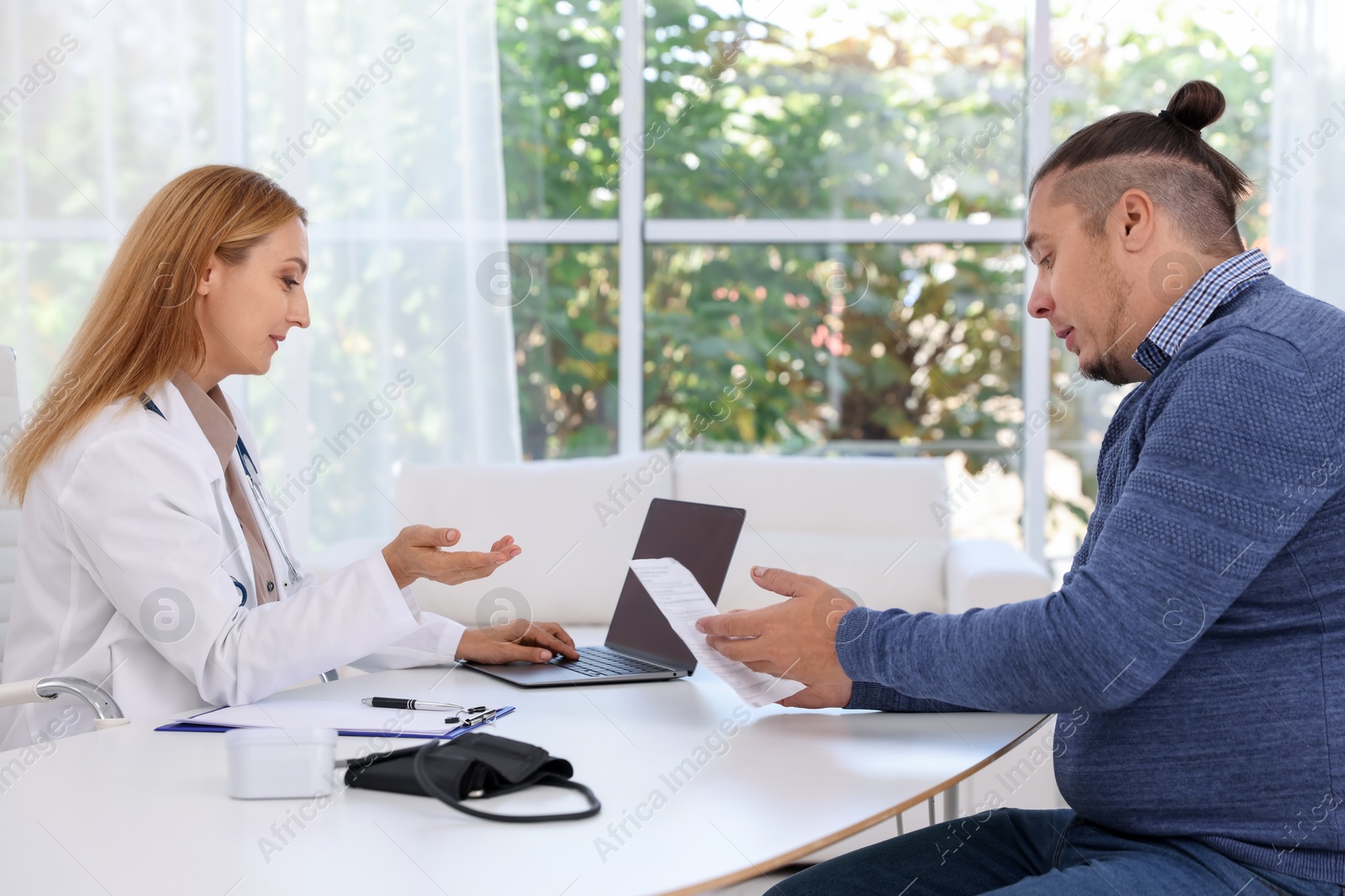 Photo of Nutritionist consulting overweight man at table in clinic