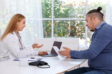 Photo of Nutritionist consulting overweight man at table in clinic