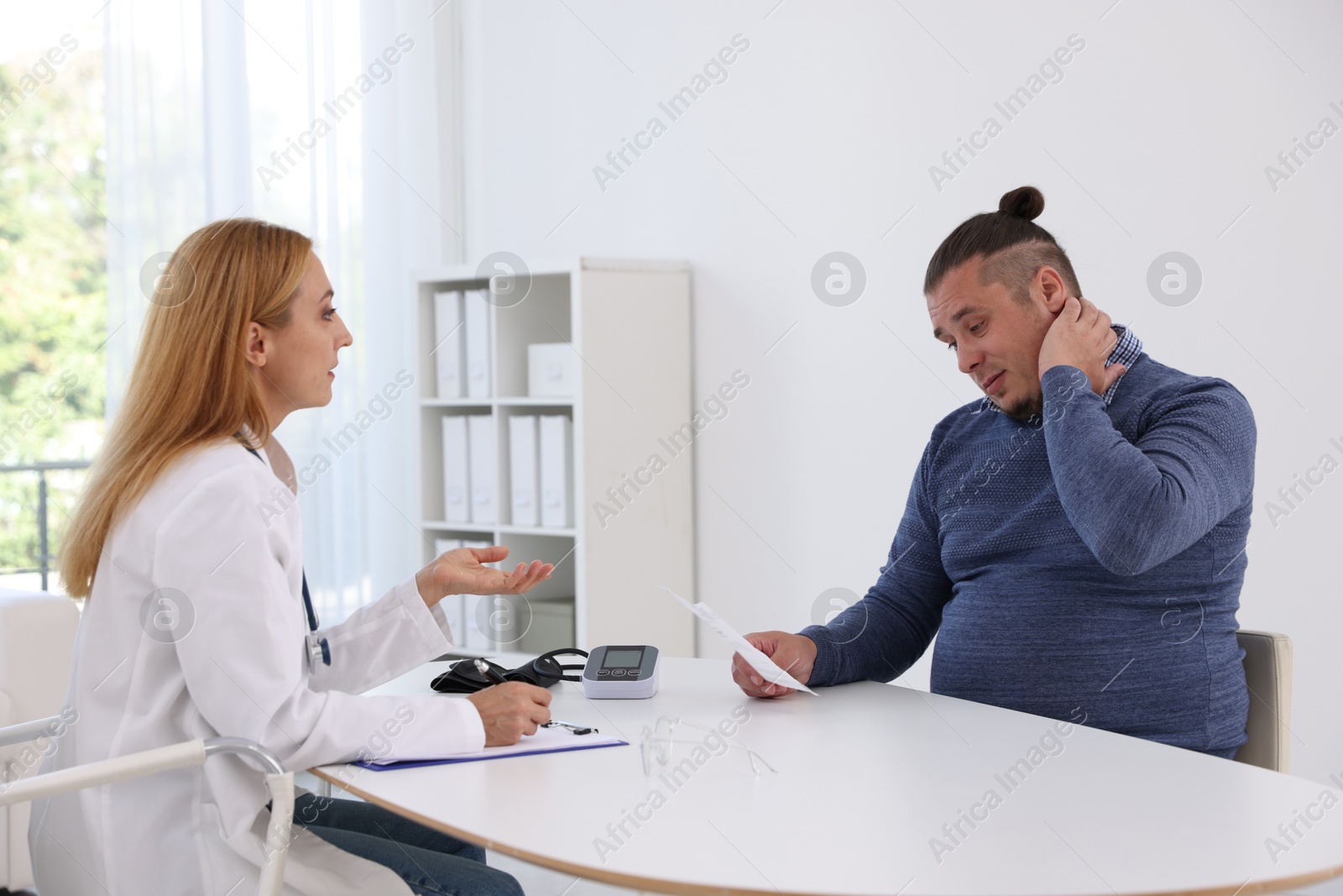 Photo of Nutritionist consulting overweight man at table in clinic