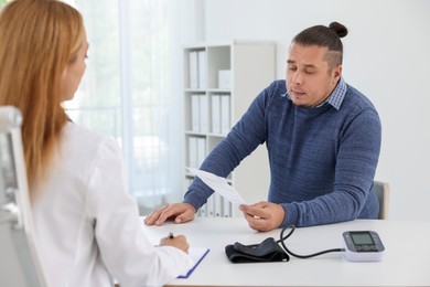 Photo of Nutritionist consulting overweight man at table in clinic